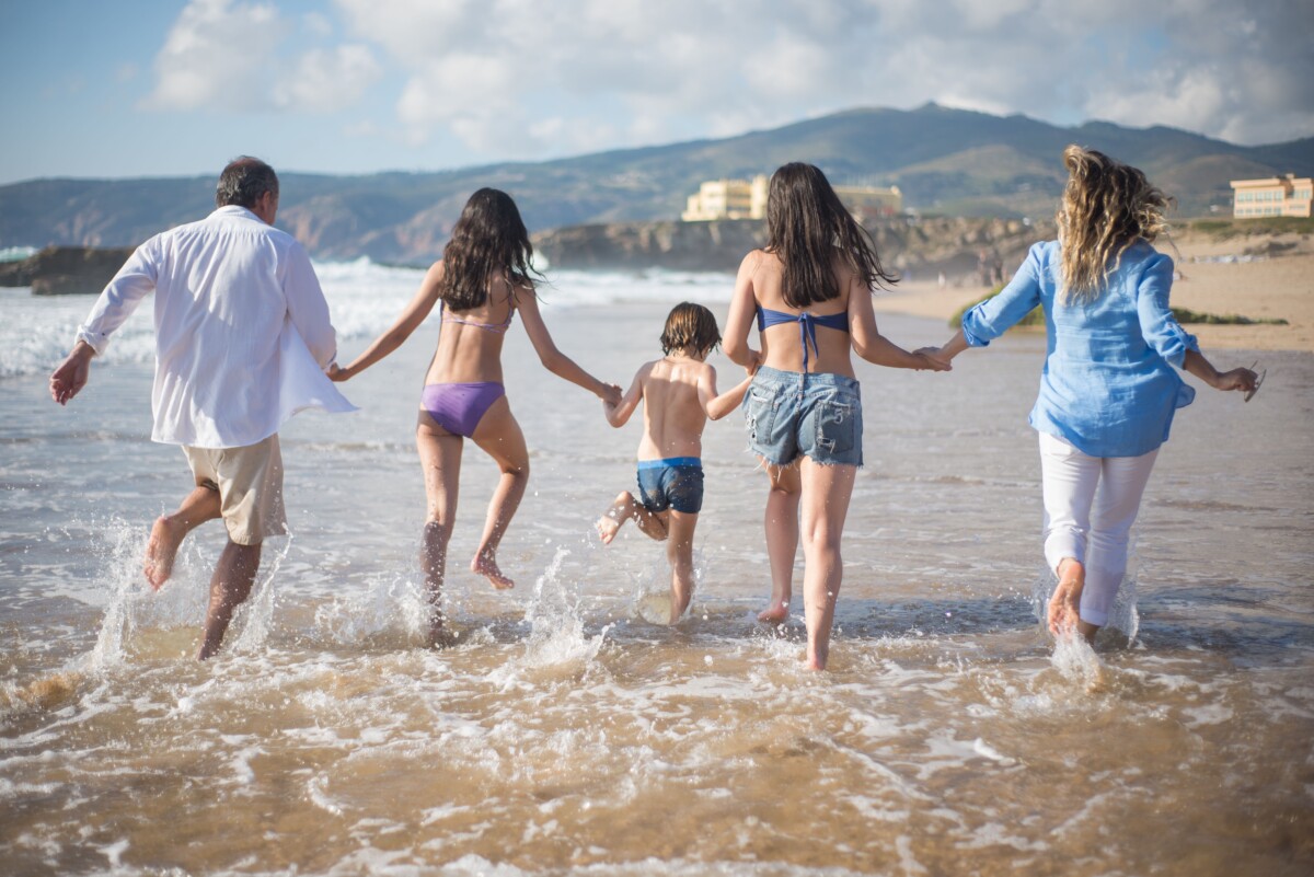 Familia corriendo hacia el mar en una playa soleada
